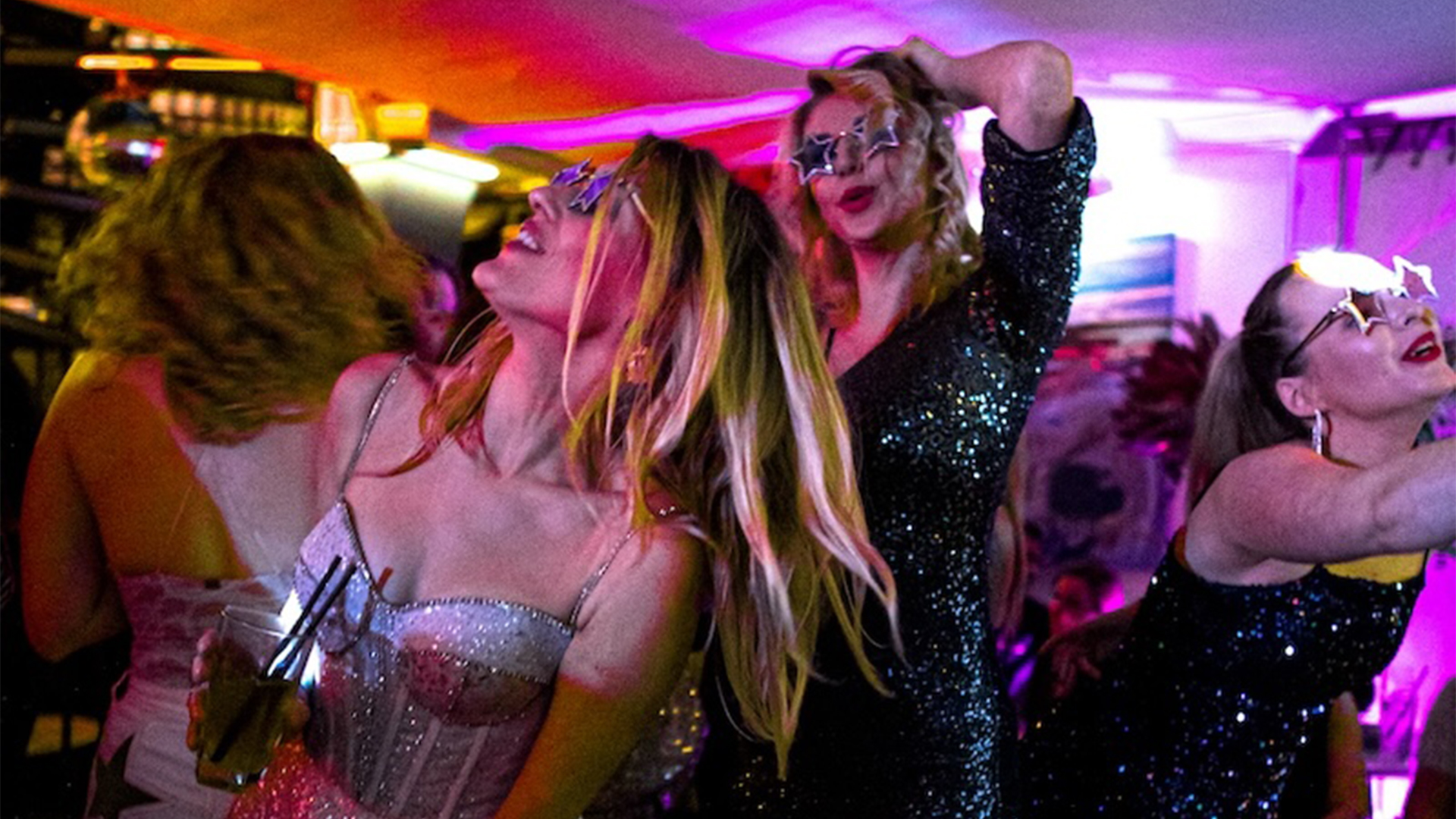 women dancing holding drinks in glittery dresses at a bristol new years eve party