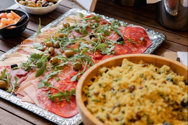 A beautifully arranged gourmet platter featuring a selection of cured meats, olives, and rocket, served alongside a bowl of flavourful couscous at The Square Club. This private hire venue in Bristol offers an exquisite buffet menu service, perfect for private parties and exclusive events in a stylish setting.