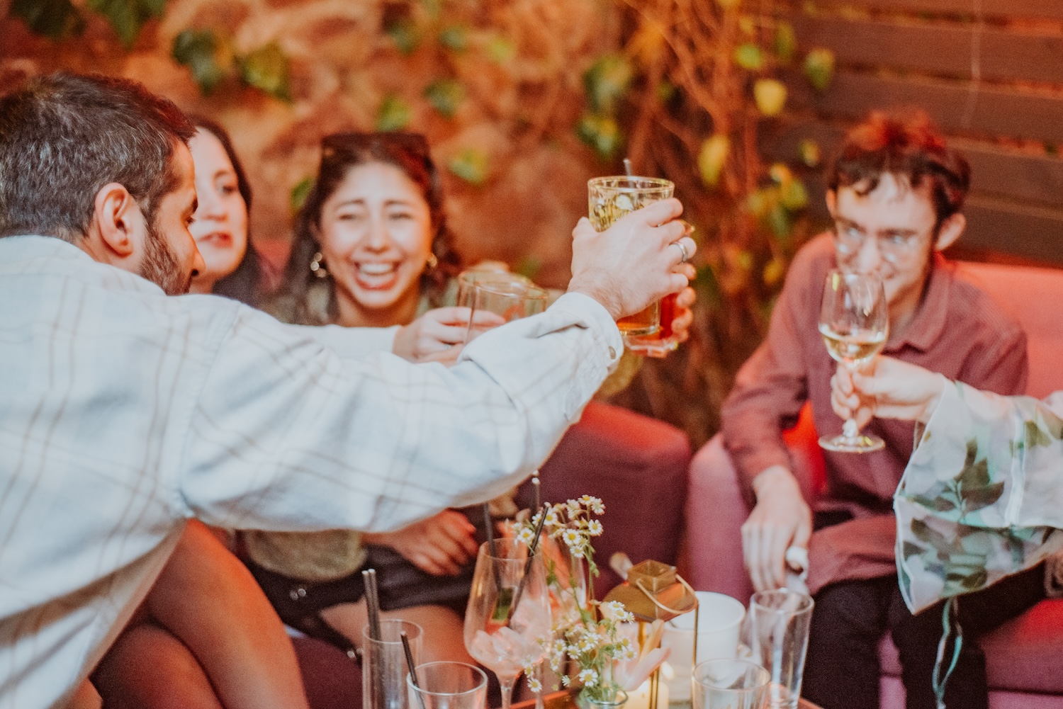 A lively group of friends clinking glasses in celebration at The Square Club, showcasing its welcoming atmosphere as a premier private events venue in Bristol. Perfect for birthdays, anniversaries, and corporate events, the space combines charm with a sense of occasion.