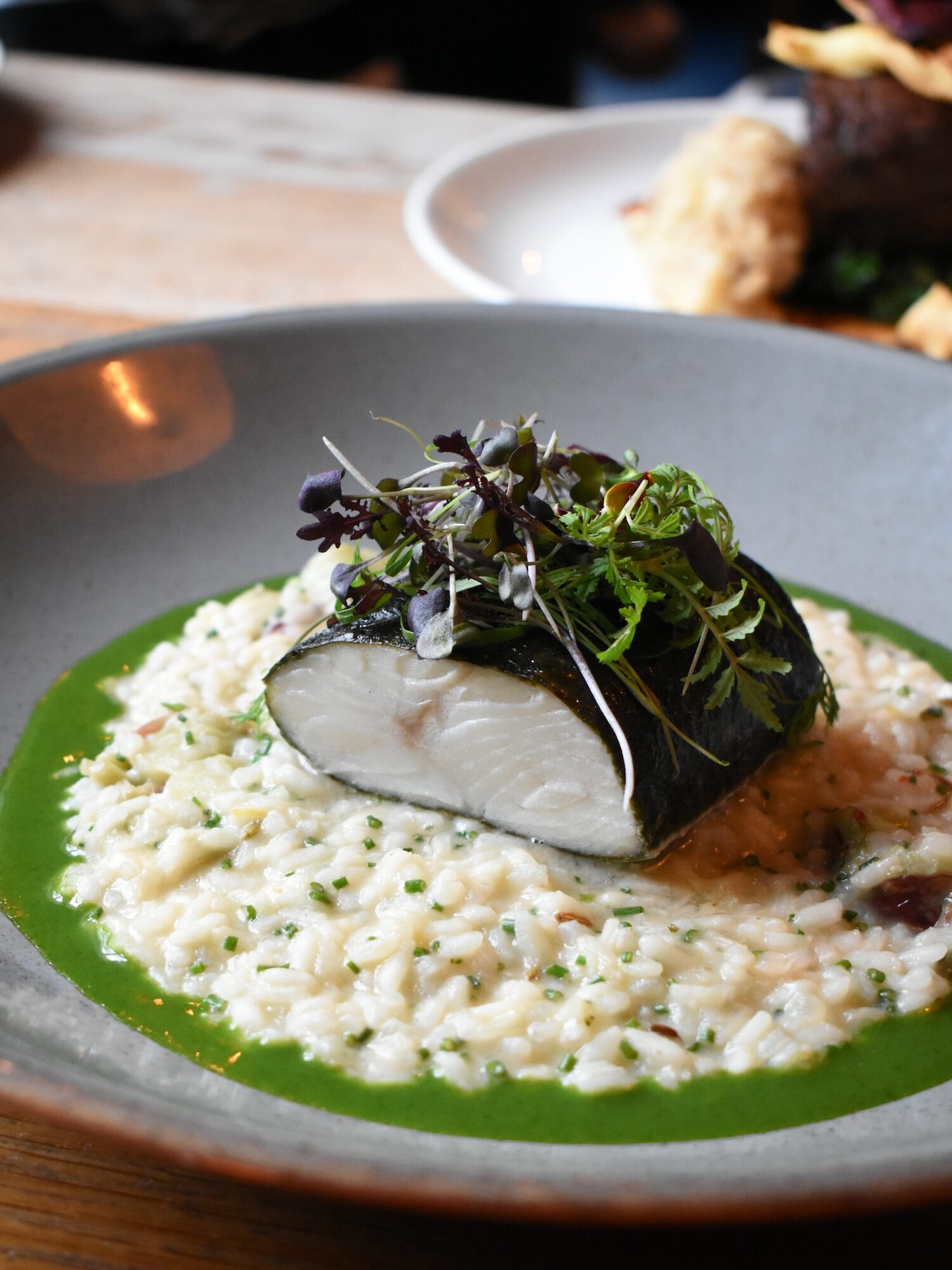 A beautifully plated dish of tender fish fillet atop creamy risotto, garnished with microgreens and drizzled with a vibrant green herb sauce. This dish, available at The Square Club in Clifton, Bristol, showcases the finest seasonal ingredients as part of the set Sunday lunch menu. Guests seeking the best Sunday lunch in Bristol will enjoy a variety of options, including this elegant seafood selection. The Square Club also offers vegetarian and vegan alternatives, ensuring an inclusive and memorable dining experience for all.