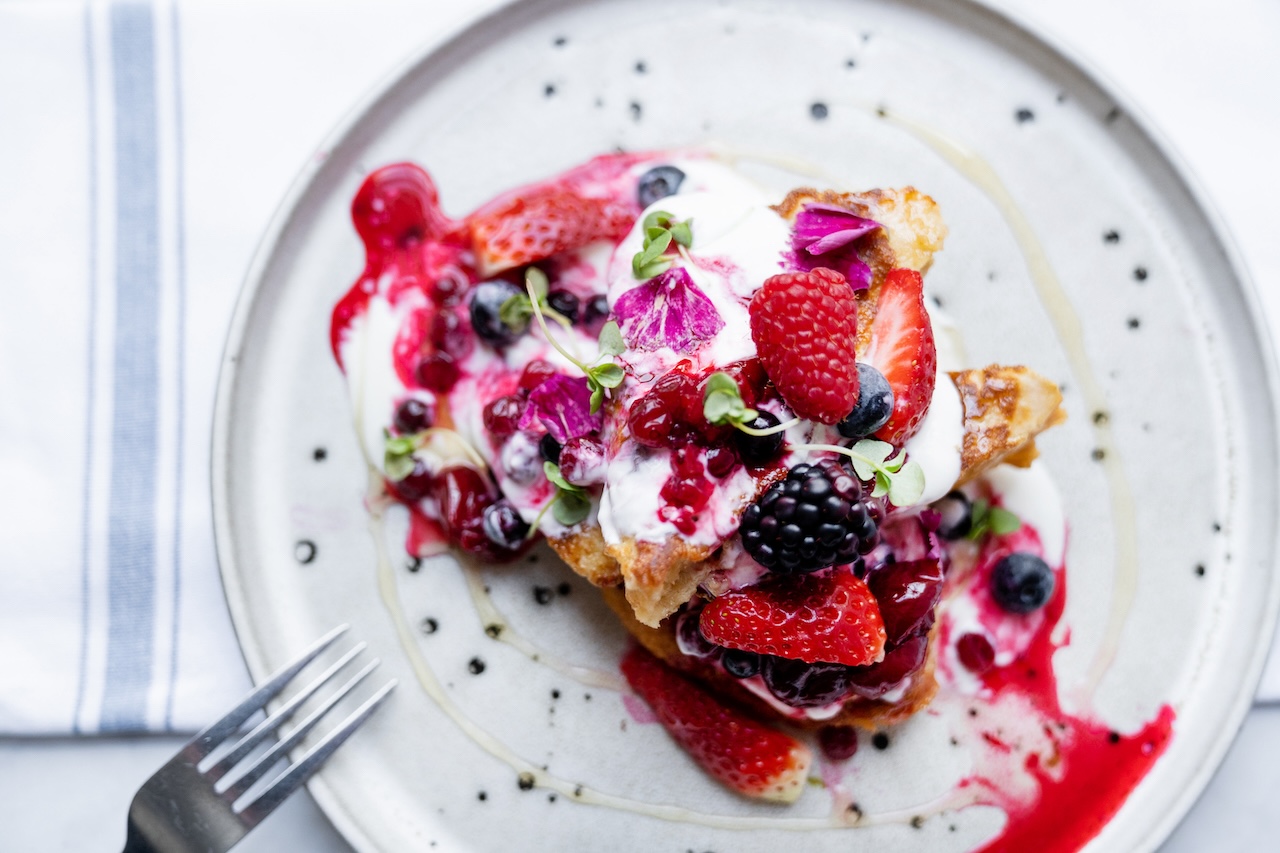 Delicious gourmet breakfast served at The Berkeley Square Hotel in Bristol, connected to The Square Club, showcasing French toast topped with fresh berries, cream, and edible flowers for an indulgent morning treat.