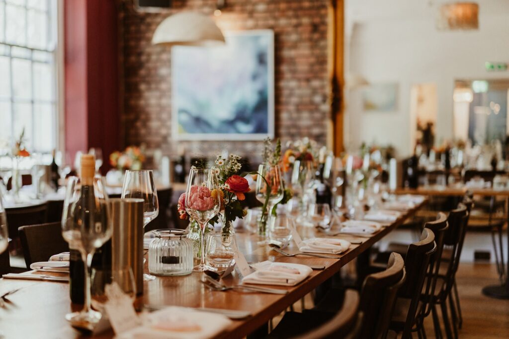 A beautifully set dining table with elegant glassware, fresh floral arrangements, and soft lighting, creating a warm and inviting atmosphere at The Square Club. This Clifton restaurant is renowned for its stylish decor and is an ideal venue for private dining, private events, fine dining, and enjoying the best Sunday Lunch in Bristol.