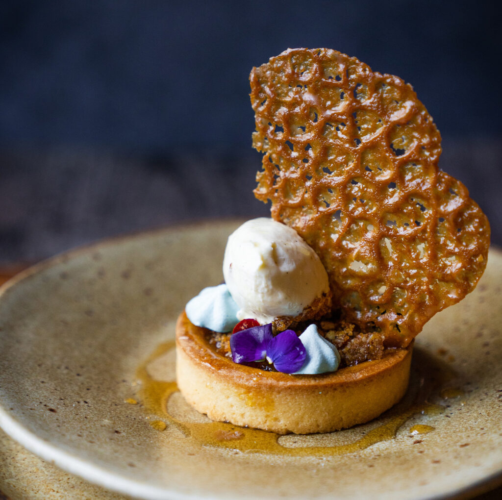 A golden-baked tart filled with rich caramelised flavours, topped with a scoop of vanilla ice cream, delicate meringue kisses, and a crisp caramel tuile. Finished with a drizzle of golden syrup and edible flowers, this dessert epitomises The Square Club restaurant’s use of the finest seasonal ingredients. Offered as part of the private dining packages, this indulgent dish is perfect for those hosting a dinner party venue or exploring private dining in Clifton or Bristol. It showcases the creativity and attention to detail that defines the club's private dining menus.